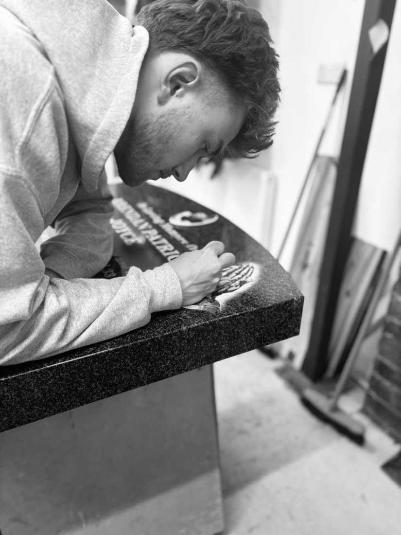 A craftsman carving and hand-finishing a memorial in the workshop
